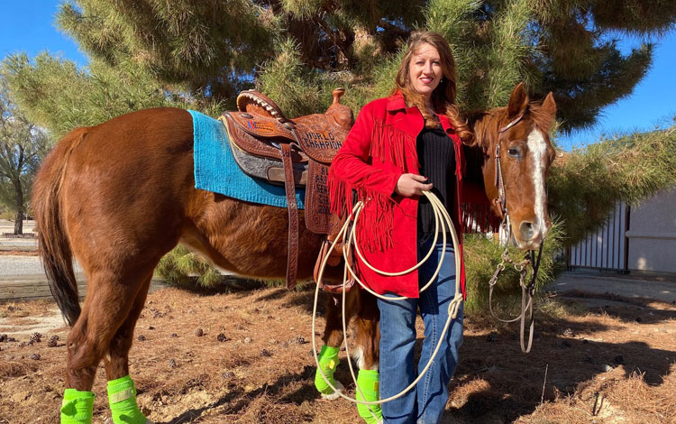 Kaylin Leas Standing next to a horse.